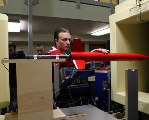 A person works on a model that appears to be a red rocket