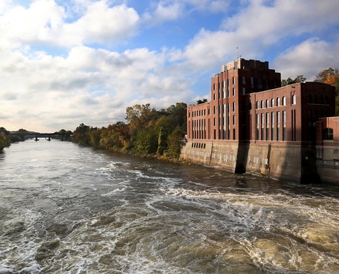 Five-story red brick building, Stanley Hydraulics Lab, set on the banks of the Iowa River in Iowa City.
