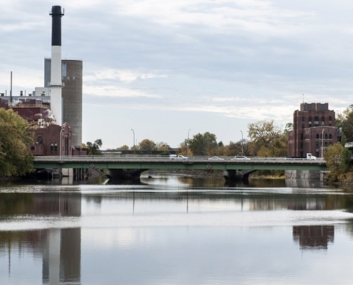 Still mirrorlike reflection on river water of the Stanley Hydraulics Lab and UI Power Plant