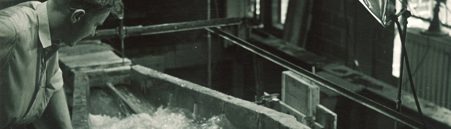 A students watches water flow through a flume in this black and white archival photo by FW Kent from the 1950s